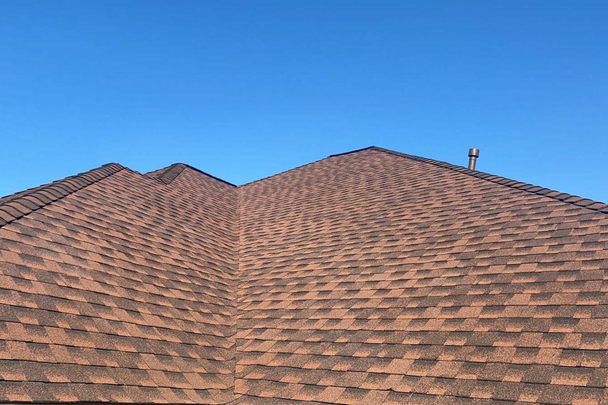 Brown asphalt shingle roof on a Houston home under a clear blue sky